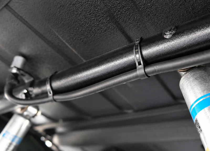 Flexroute rubber clamp keeping underbody tubing secure and vibration-free near vehicle suspension.