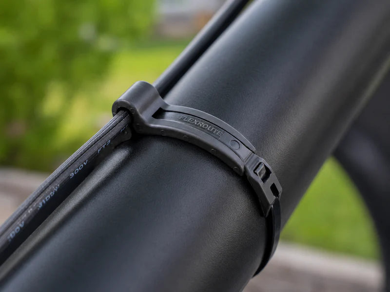 Close-up of a Flexroute rubber clamp routing a black cable smoothly along a UTV roll cage