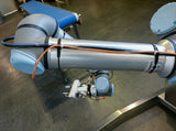 Flexroute TPV clamp guiding an orange pneumatic line along a metallic industrial robot arm.