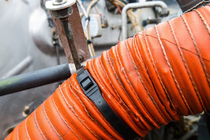 Heavy-duty Cobra low profile cable tie securing a thick orange corrugated industrial intake hose.