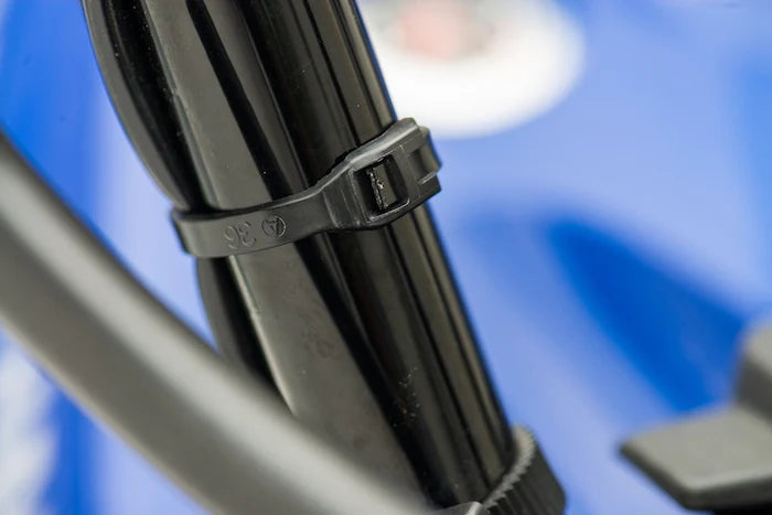 Cobra low profile cable tie strapping a wire harness securely to a metal chassis tube on an off-road vehicle.