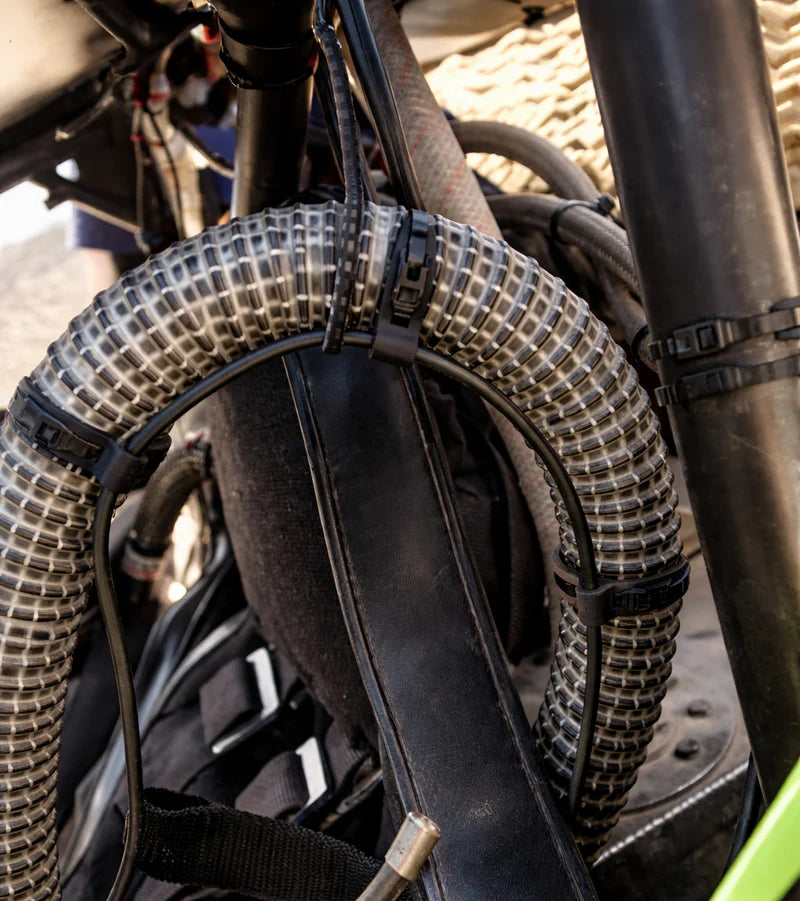 Flexroute rubber line clamp fastening a protective braided wire loom to a vehicle chassis.