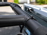 Flexroute TPV rubber line clamp securing a wire harness along a black vehicle roll bar.